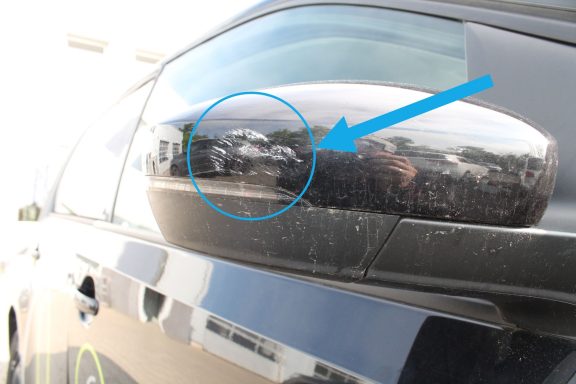 Kerbende Verschrammung Seitenspiegelschale Detailansicht eines Autospiegels mit reflektierenden Objekten im Hintergrund.
