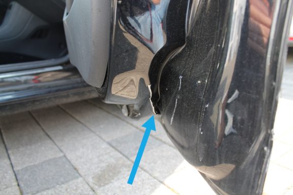 Beifahrertür innen Material gebrochen und deformiert Schaden am unteren Rand einer Autotür, deutlich sichtbar mit blauer Pfeilmarkierung.