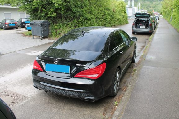 Ansicht hinten rechts Schwarzer Mercedes auf einem Bürgersteig, geparkt in einer grünen Umgebung.