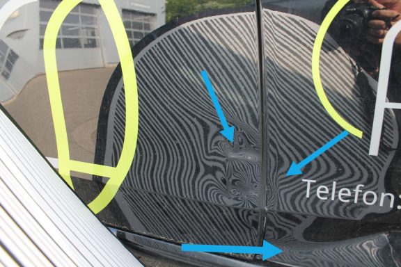 Seitenschaden Verformung mit Dellensegel Detailaufnahme einer Fahrzeugoberfläche mit Linienmustern und Markierungen.